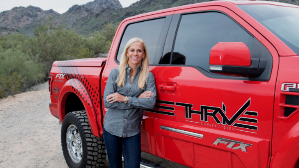 Danielle Bryant, owner of THRIVE Construction, stands next to a red THIVE truck.