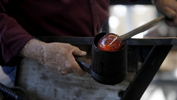 Person holding hot glass to mold