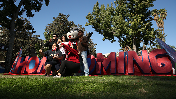 Students pose with TimeOut in front of homecoming letters.