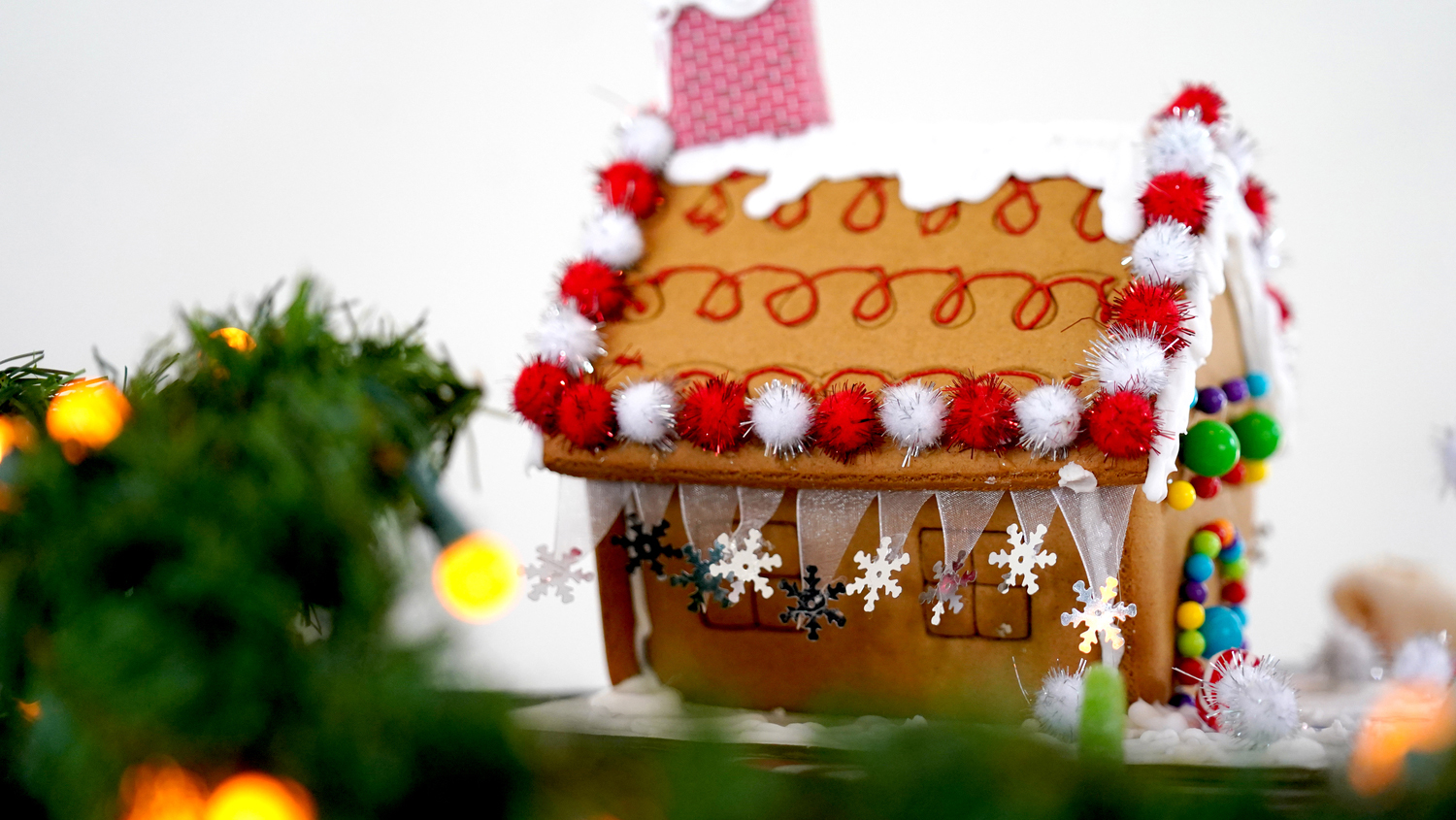 Gingerbread house next to greenery with yellow lights