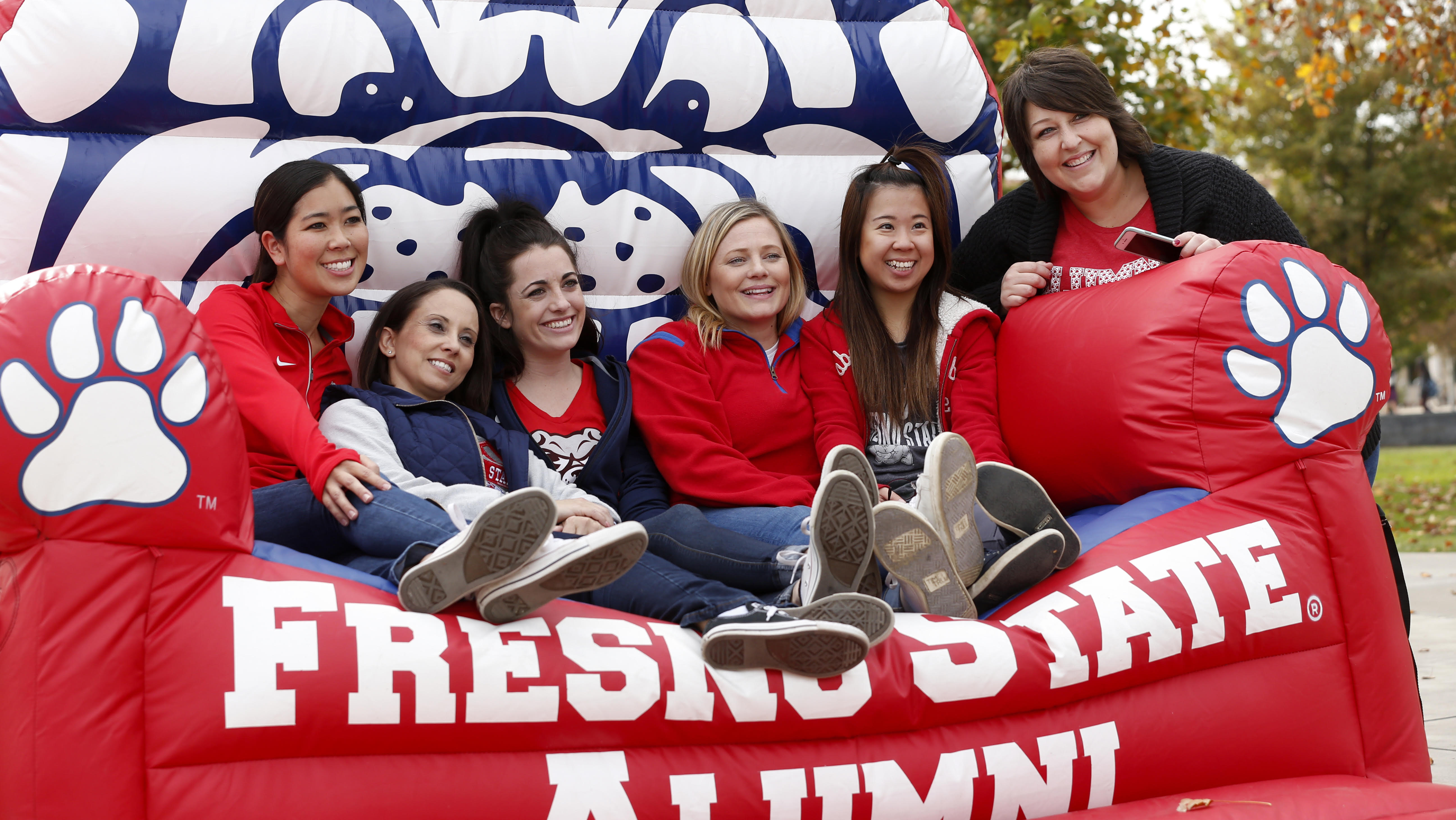 Asheline Beeson and other employees on an overstuffed inflated chair that says Fresno State alumni