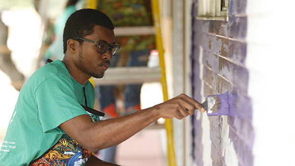Student volunteer painting a building.