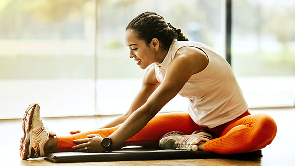 Woman sitting on yoga mat stretching