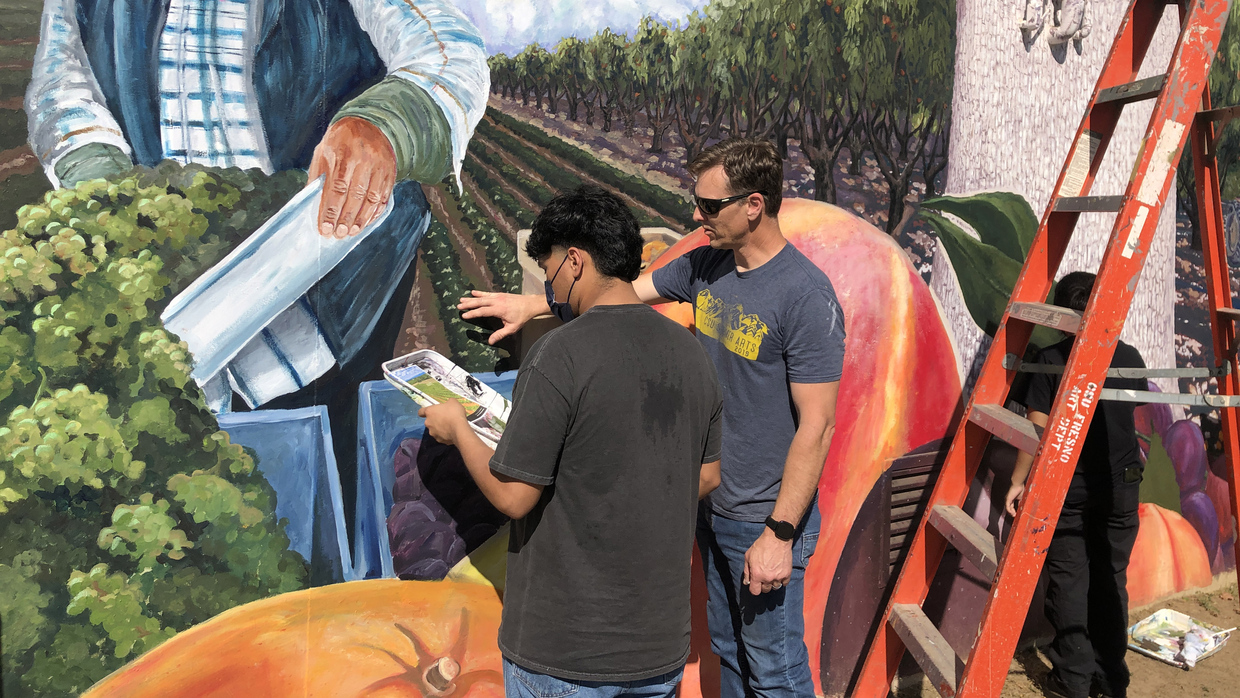 Professor Adam Longatti, art and design department, instructs a student on a mural project