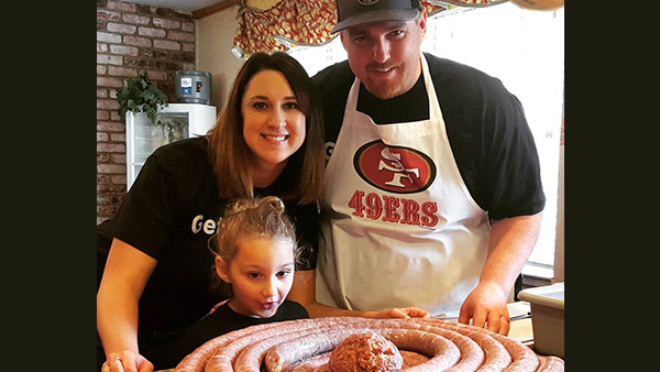 Amanda with her daughter and husband making sausage.