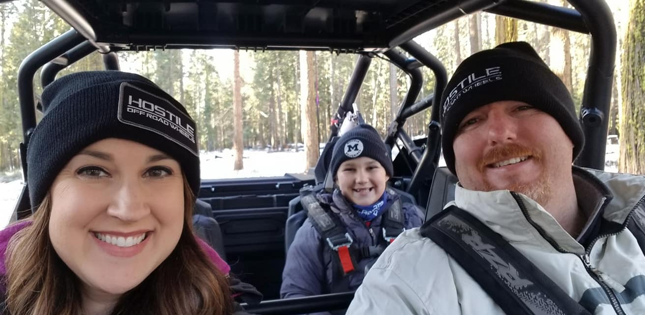 Amanda with her daughter and husband off-roading in the snow.