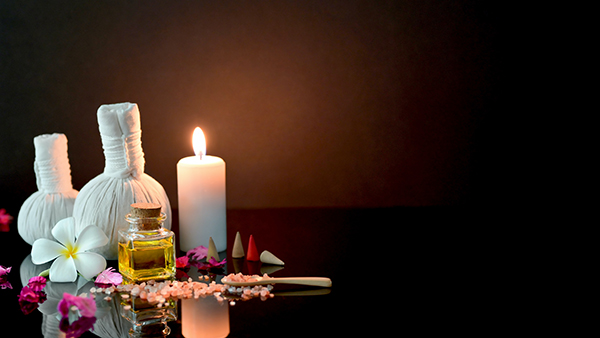 Candle, towels, perfume, and flower with bath salts in a dark room. Showing serenity.