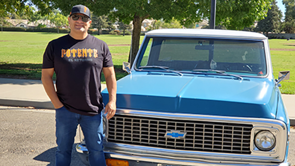 Dr. Irán Barrera standing next to his classic blue Chevy pick-up truck.