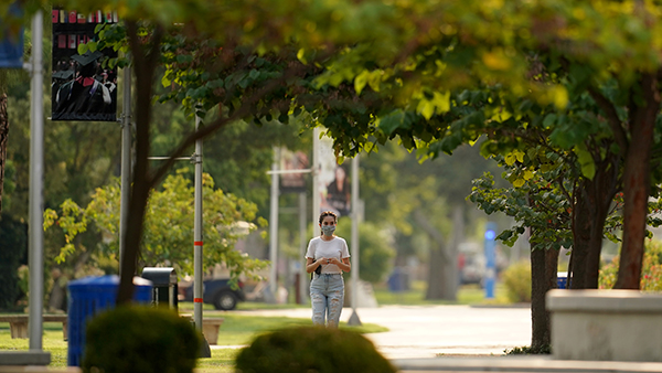 Masked student walks through campus.