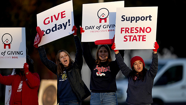 Fresno State students and staff promoting Day of Giving with signs.