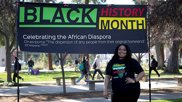 Young lady standing in front of a Black History Month sign.