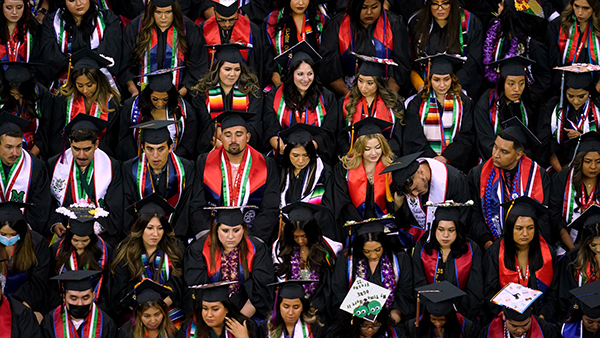 Fresno State graduates in commencement robes sitting during graduation ceremonies.