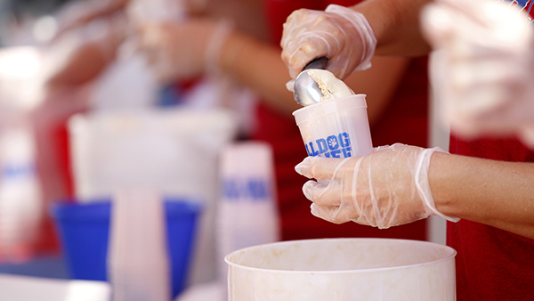 Gloved hands scooping ice cream.