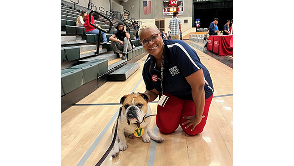 Wendy Nelson kneeling on gym floor with Victor E. Bulldog IV. g