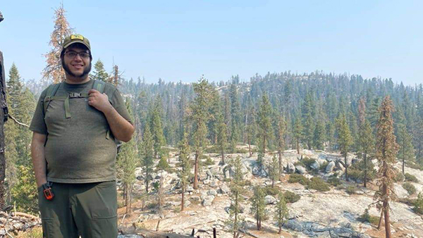 Dr. Petros Chrysafis standing in the mountains with trees behind him.