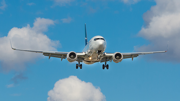 Airplane flying in the blue sky with white clouds surrounding it.