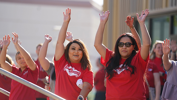 Staff in red t-shirts with hands over their heads.