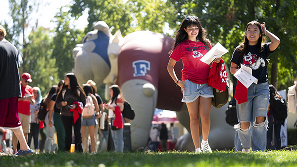 Female students walking at an event smiling