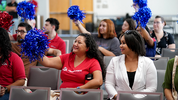 Fresno State staff wave blue pom poms in the air.