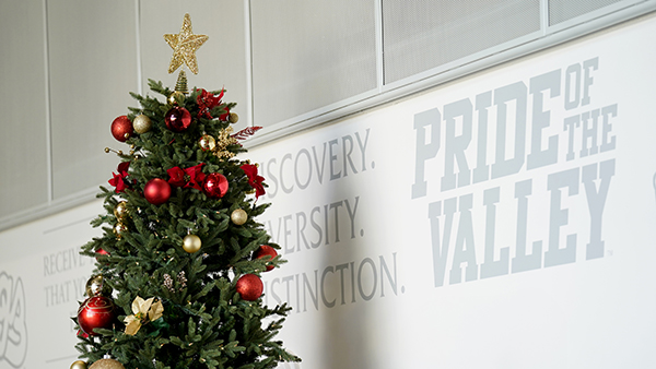 Christmas tree in the Resnick Student Union next to wall vinyl that reads Pride of the Valley.