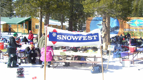 Snowfest sign in the snow with employees enjoying the day.