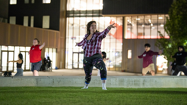 People doing yoga in the Leon S. Peter's Event Plaza behind the Resnick Student Union at night.