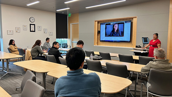 Meeting room with people seated and a speaker in front of the class.