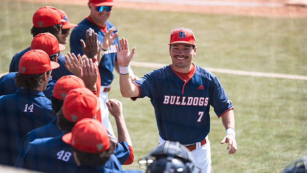 Fresno State baseball player giving high fives to the team.