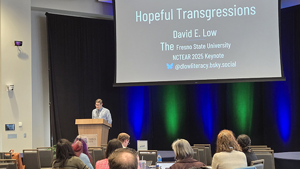 Dr. David Low stands at a podium speaking to a room of people.