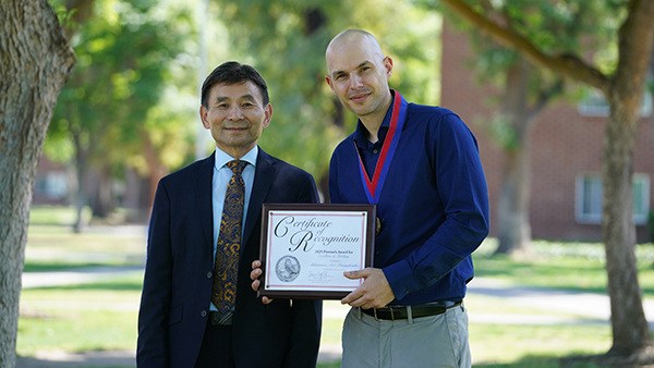 Dr. Xuanning Fu, Fresno State provost and vice president for Academic Affairs on the left standing with Dr. Dr. Aris Athanasios Panagopoulos who is holding a Certificate of Recognition.