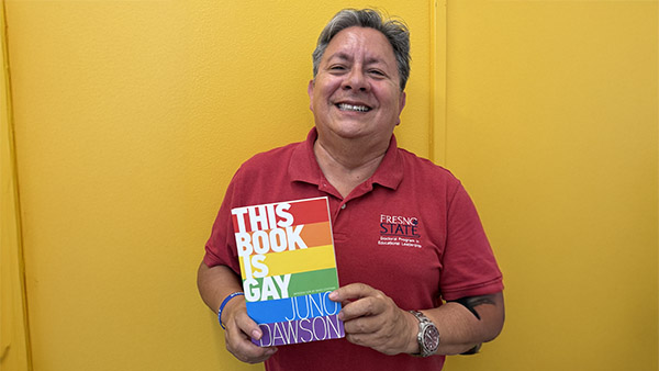 Dr. Peter Robertson holding the book "This Book is Gay"