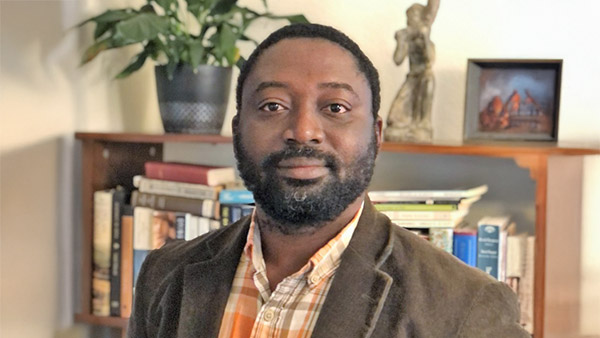 Dr. Reuben Addo in front of a book shelf