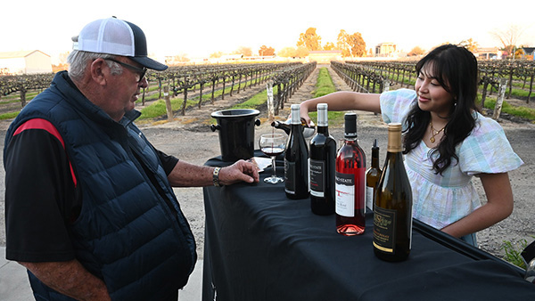 Fresno State wine student pouring wine for guests at wine tasting event on campus farm