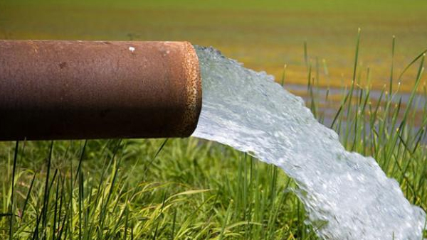 Water coming out of pipe in field