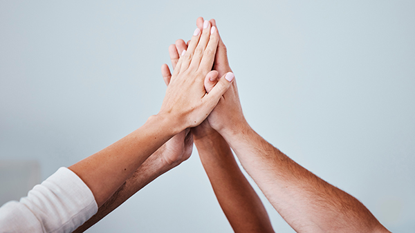 Stock photo of four hands high-fiving.