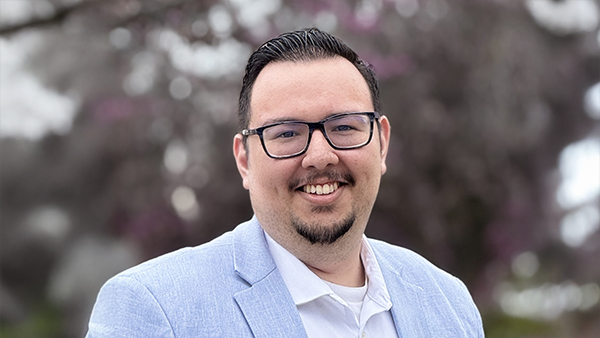 Portrait of Jose Medina III in front of a pink blooming tree.