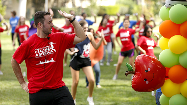 Group workout outside on lawn with an apple balloons and orange, yellow and green balloos on the right side.