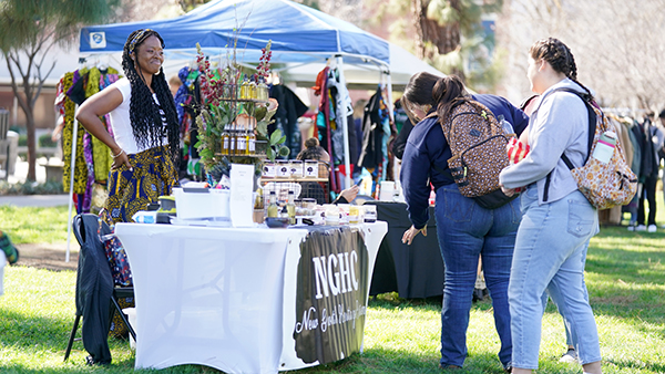 Two female students looking at a table of goodies during Black History Month festivities.