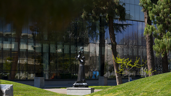 Statue of Jane Adams lifting a child outside of the Fresno State Library.