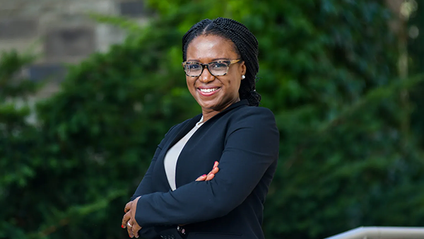Outdoor portrait of Dr. Ifeoma Ajunwa with arms crossed in front of her.