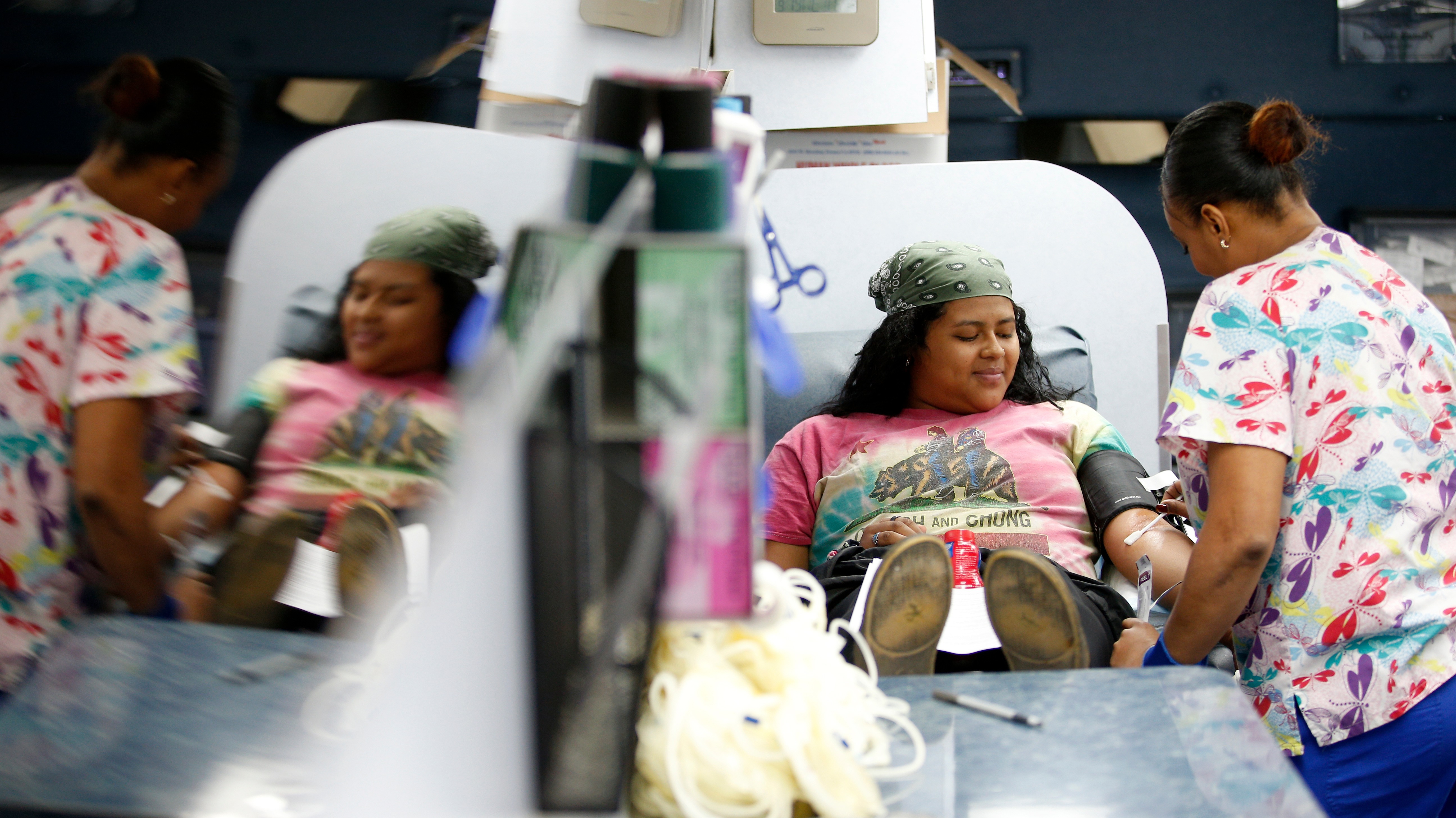 Student laying in blood drawing chair with nurse to her left