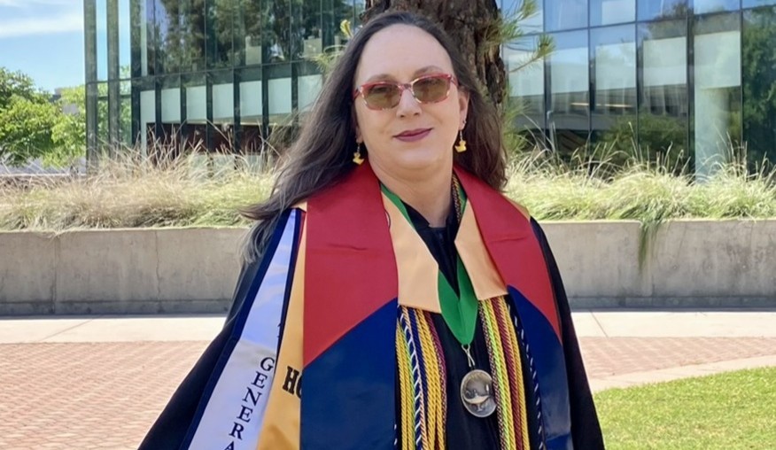 Michele Falk posing in graduation regalia