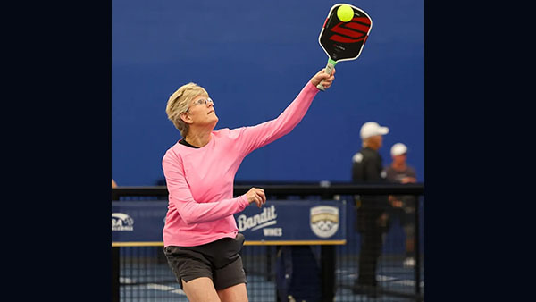 Katha Brassfield  in pink long sleeve top playing pickleball.