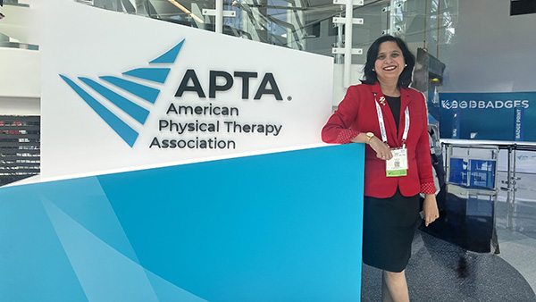 Dr. Nupur Hajela next to American Physical Therapy Association (APTA) sign