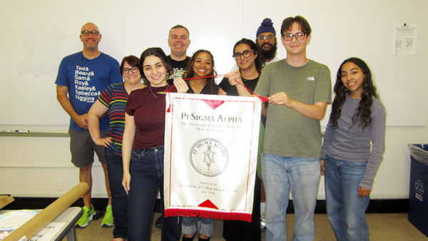 Multiple members of Pi Sigma Alpha, with two holding a banner for their organization.