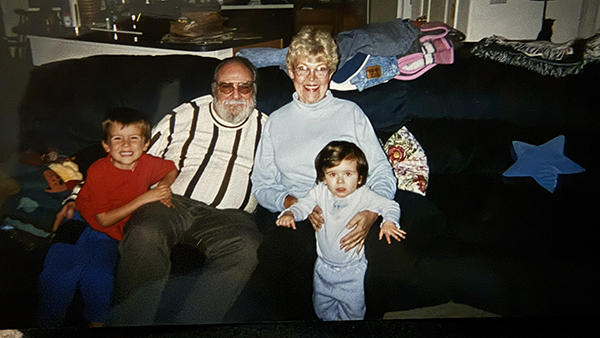 Dr. Max Futrrell (center) with a child (left) and his wife (right) sitting on the couch holding another child in front of her