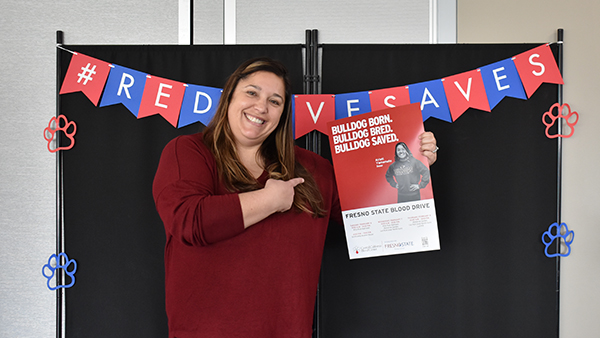 Woman holds a Fresno State Blood Drive poster.