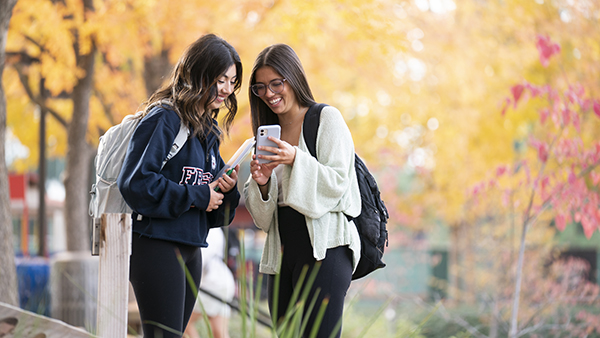 Two female students looking at a cell phone.