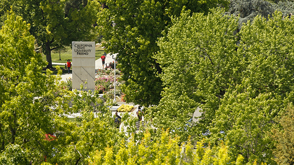 The Fresno State monument in the center of campus surrounded by trees.