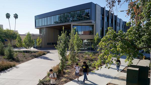 Photo of the Resnick Student Union with students walking down the side walk.